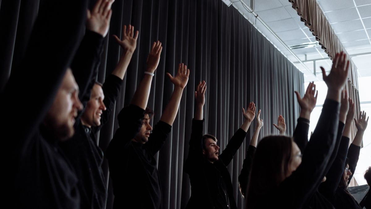 A dynamic group performance with raised arms and synchronized movements indoors.